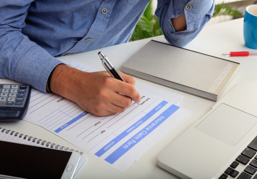 Man fillimg an Insurance Claim Form in an office background